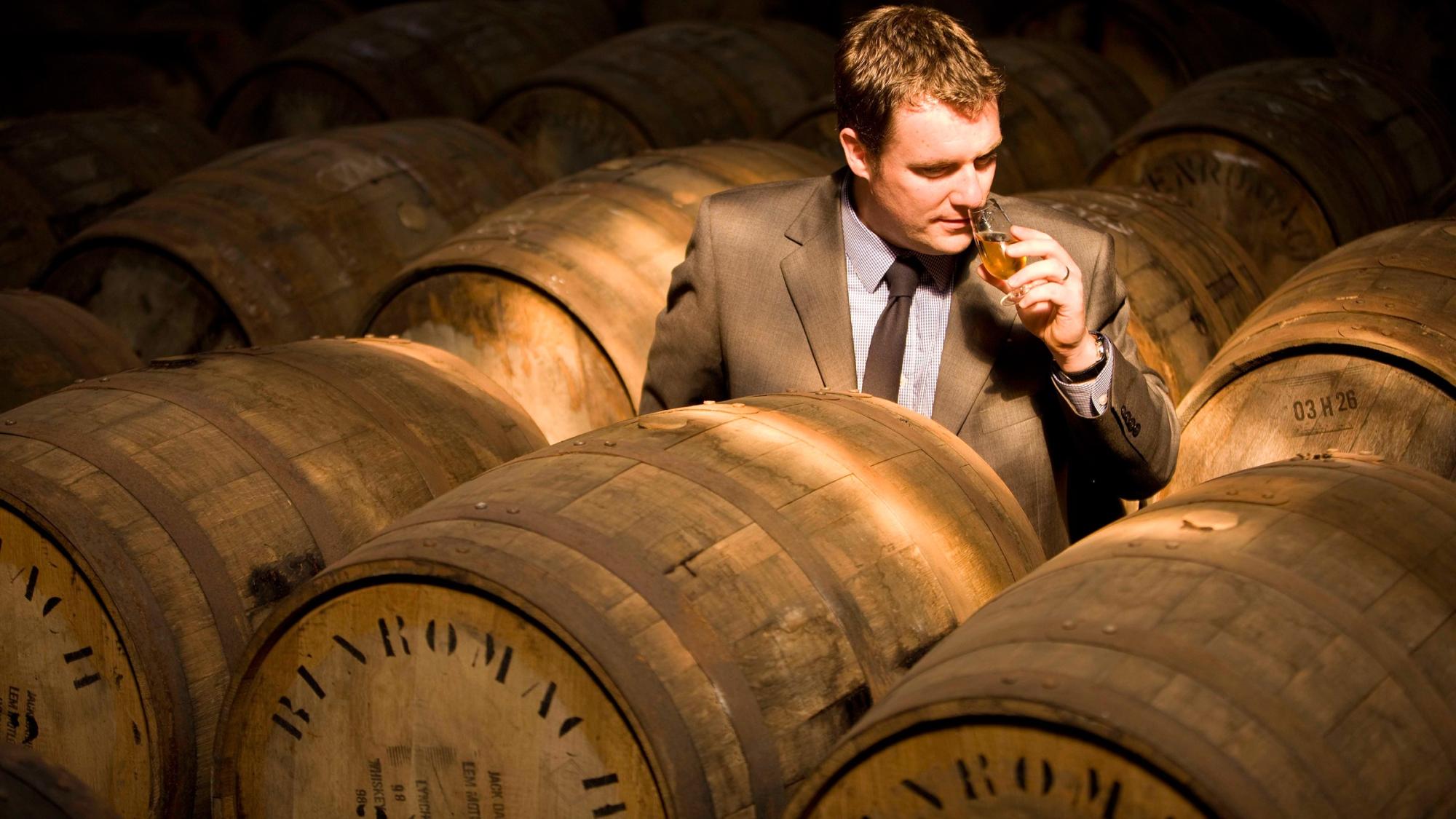 Gordon & MacPhail whisky taster among maturing oak casks in the warehouse